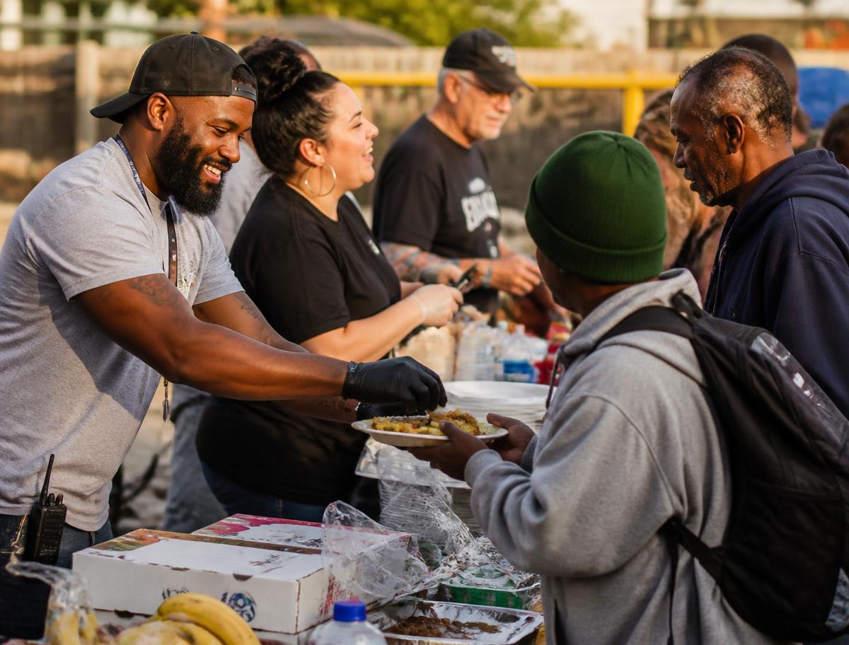 Volunteers of different ages and backgrounds serving food together at a community outreach table